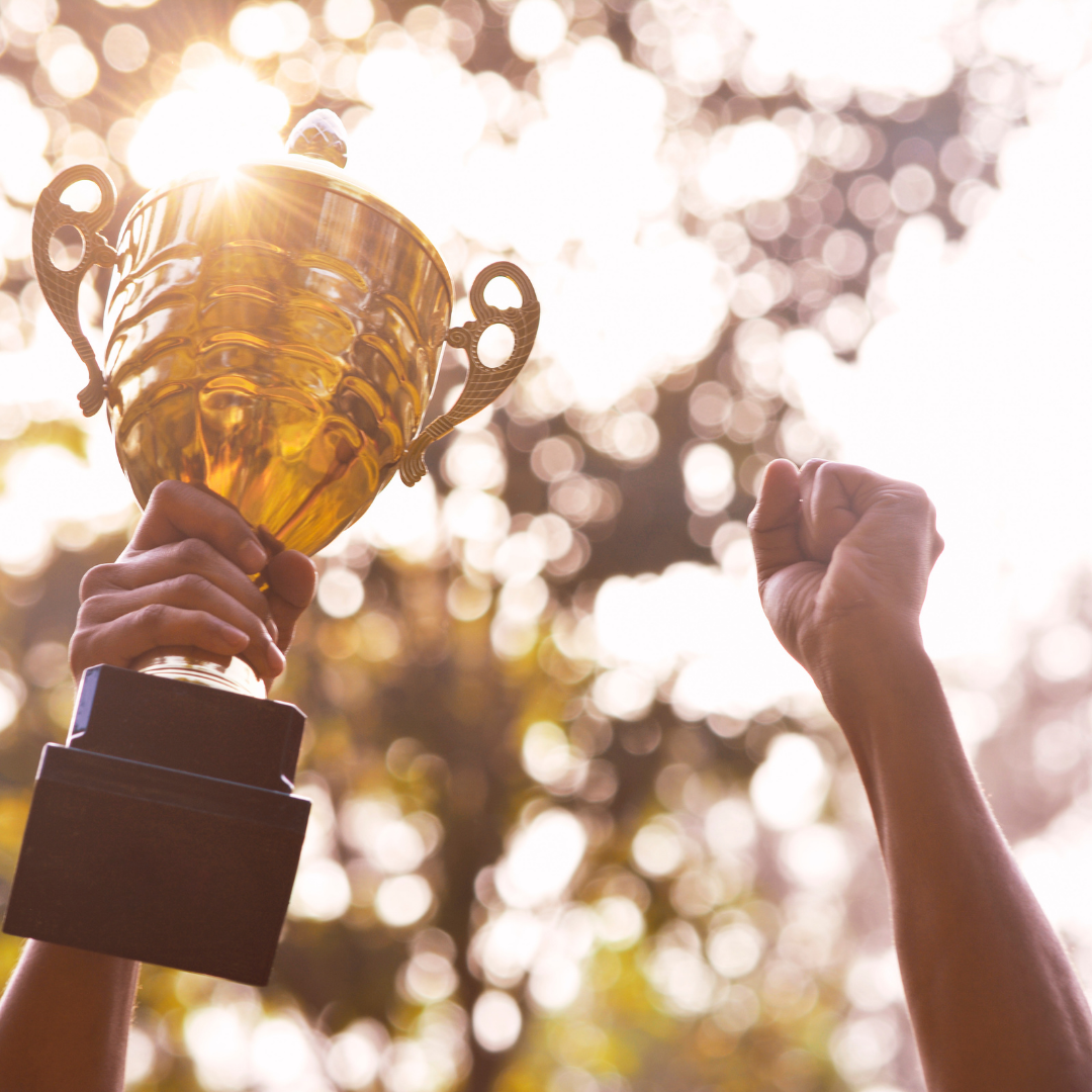 picture of someone holding up a gold trophy with blurred trees in background
